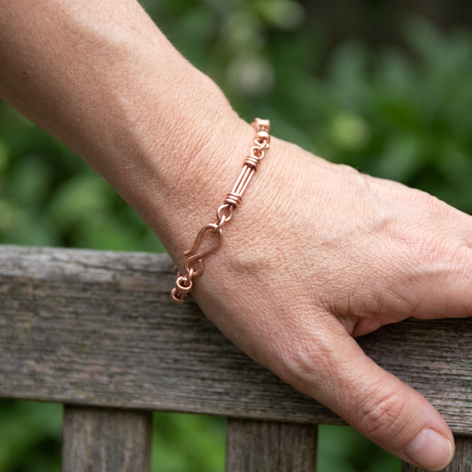Copper bar link bracelet on a woman’s wrist in natural outdoor light