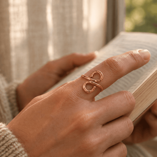 lovely hammered copper ring on womans hand as shes reading a book in the afternoon sunshine