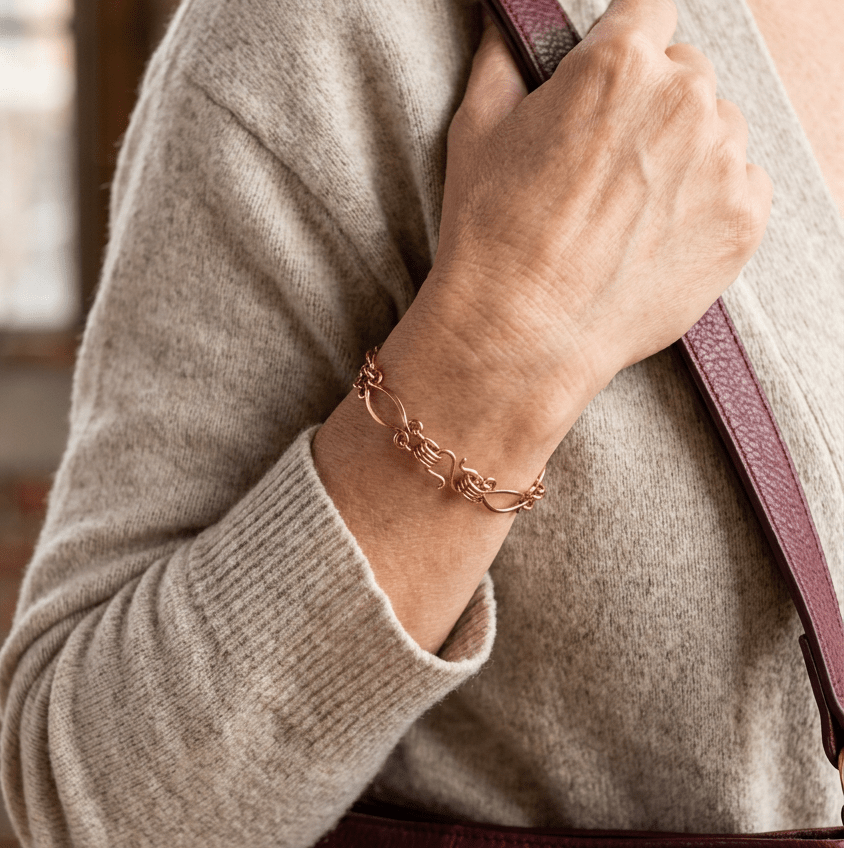 Echo copper bracelet lifestyle shot with oatmeal cardigan and burgundy leather purse
