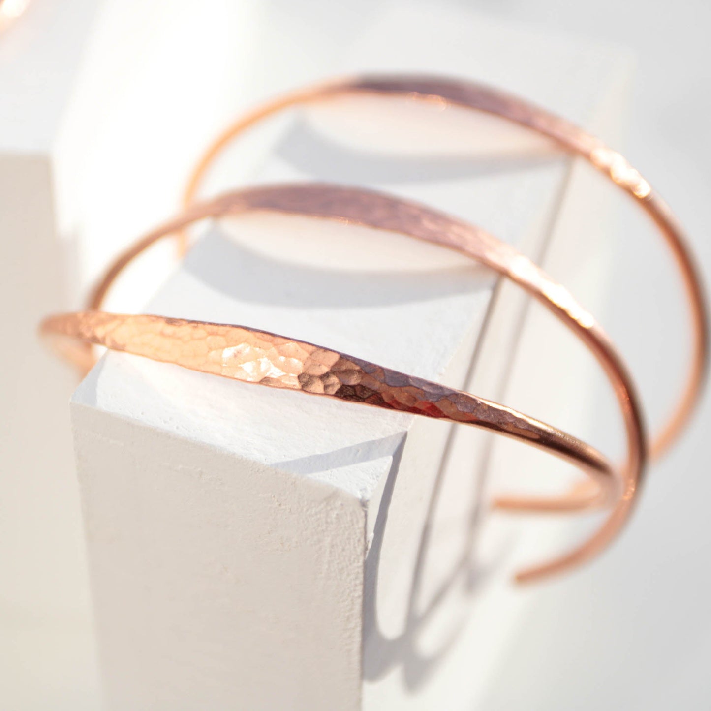 Minimalist hammered copper cuff bracelet with a reflective texture and warm golden glow
