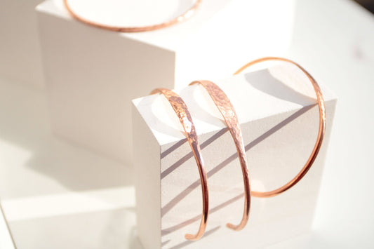 Minimalist hammered copper cuff bracelet with a reflective texture and warm golden glow