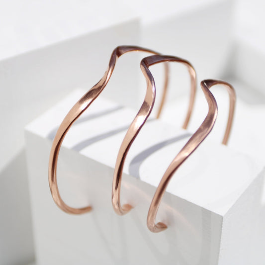 handmade copper wave cuff bracelet on white background