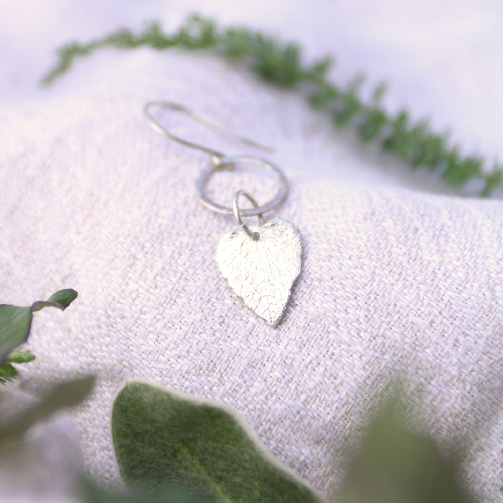 Dead nettle fine silver charm earrings with herbs on linen background handmade carrie foscato design