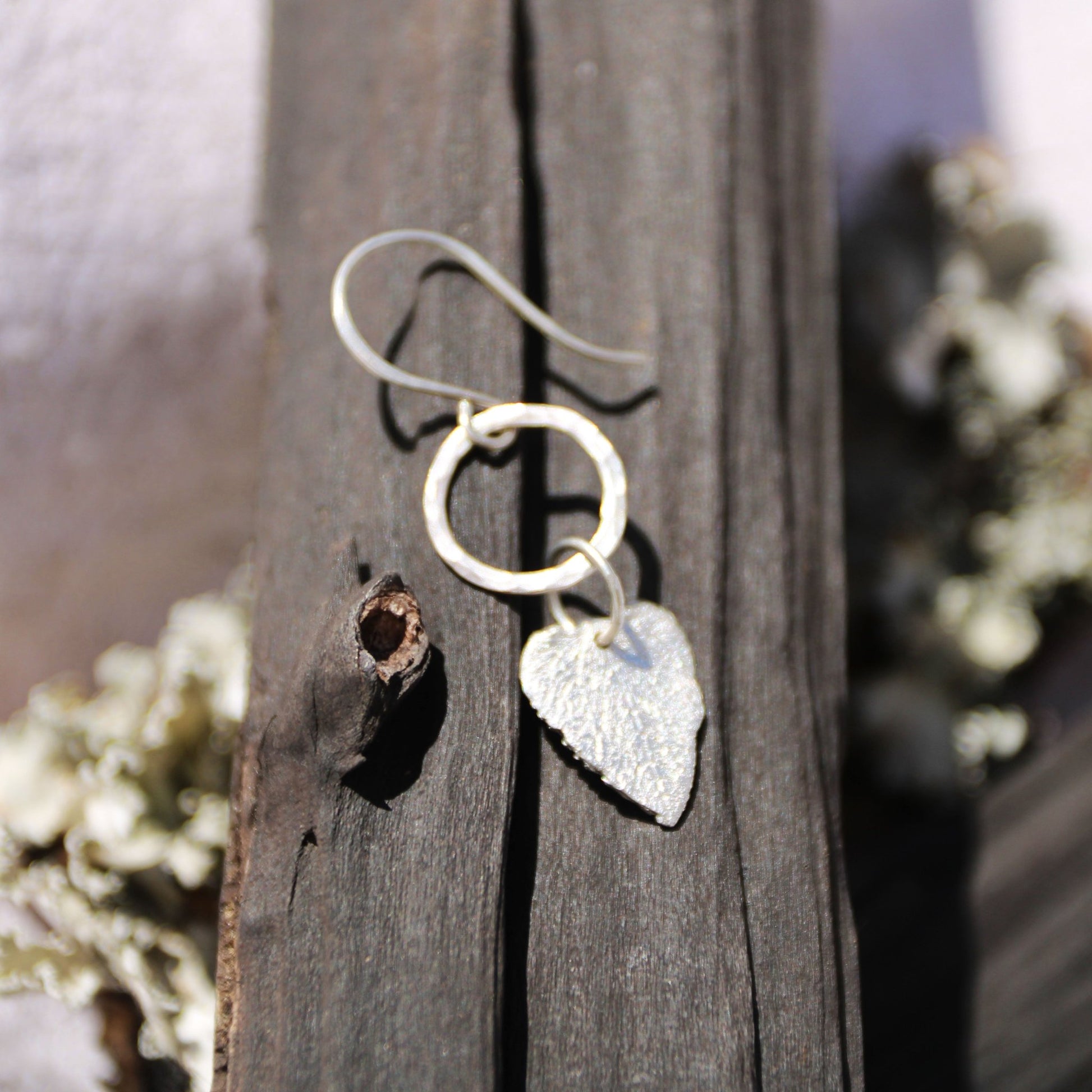 Fine silver Dead nettle heart-shaped earring on a wooden surface with blurred natural background