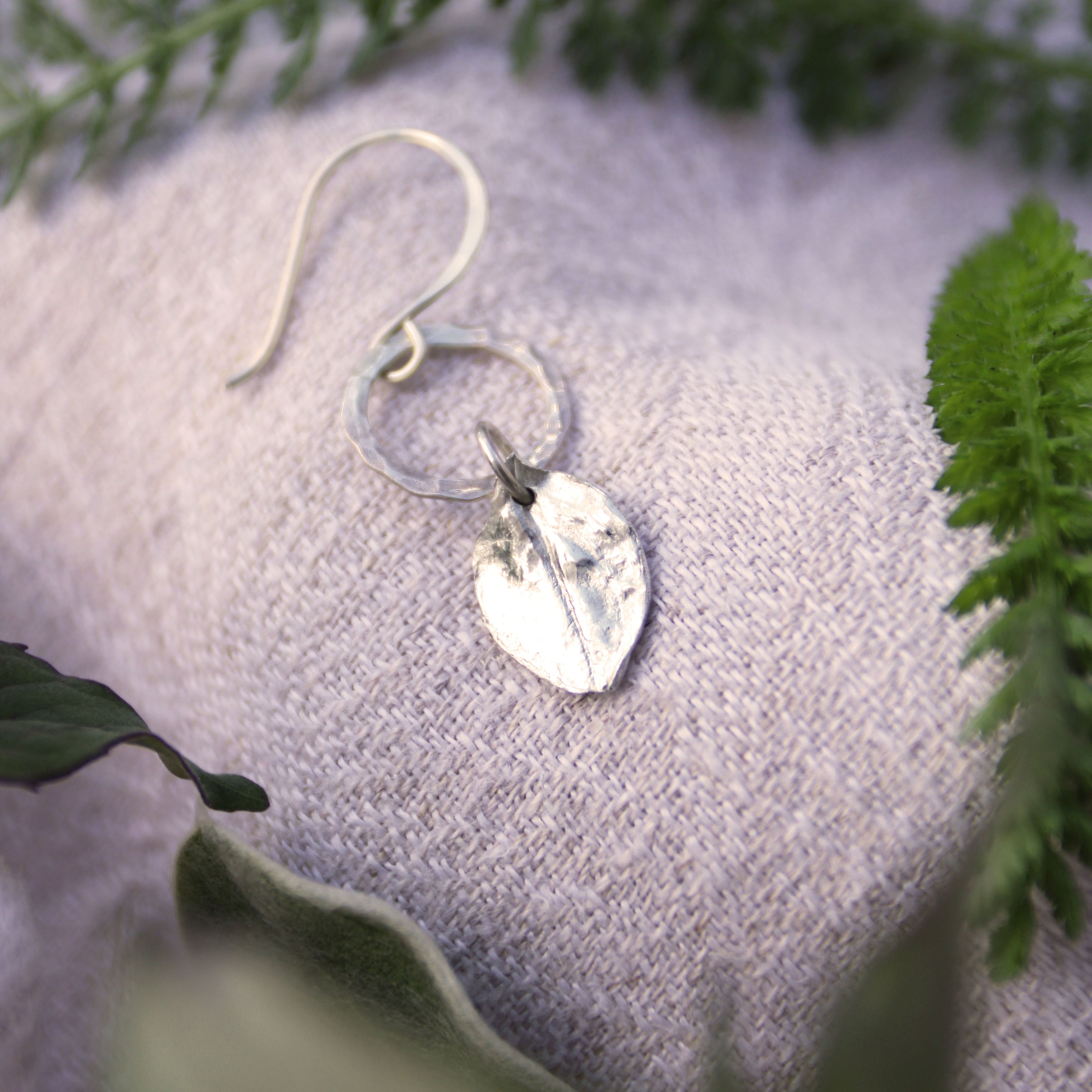 fine silver echinacea charm earrings on linen background with herbs