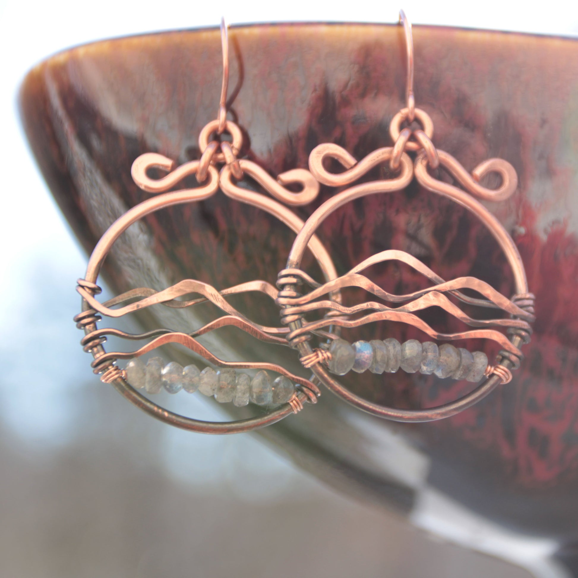 Copper earrings with gemstones on a dark, textured surface