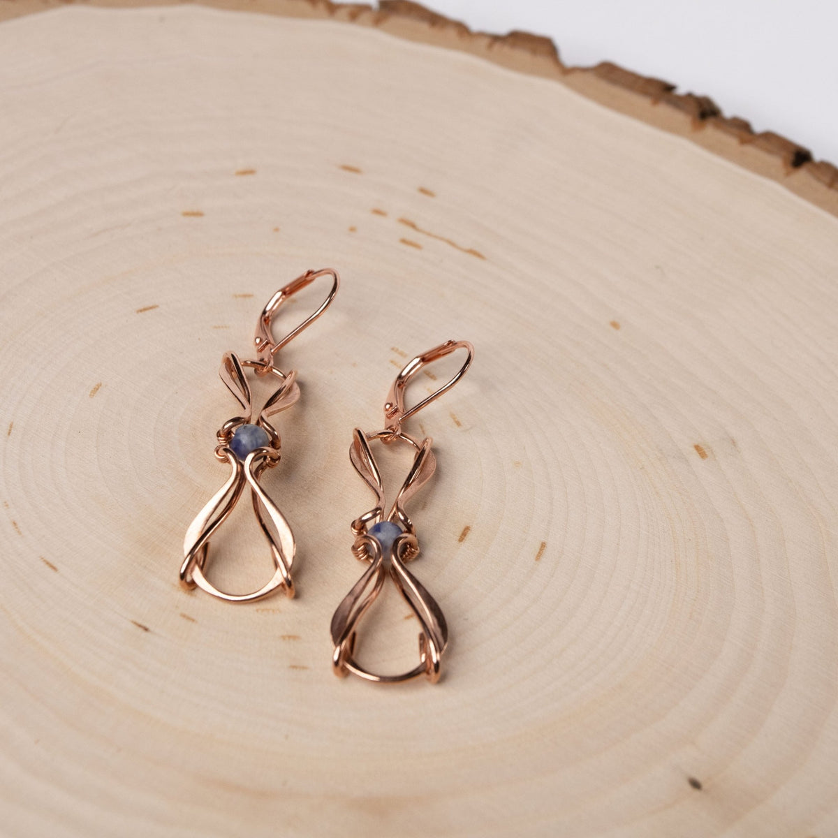 copper wire wrapped earrings with blue stones on wood