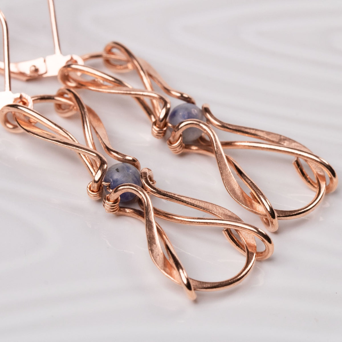 closup of wire wrapped copper earrings with blue stones carrie foscato design
