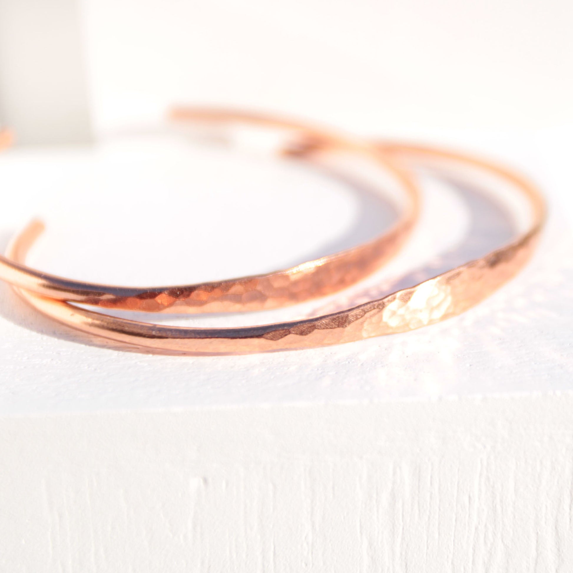 Minimalist hammered copper cuff bracelet with a reflective texture and warm golden glow