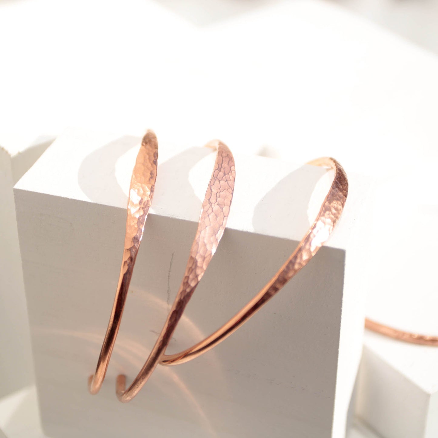 Minimalist hammered copper cuff bracelet with a reflective texture and warm golden glow