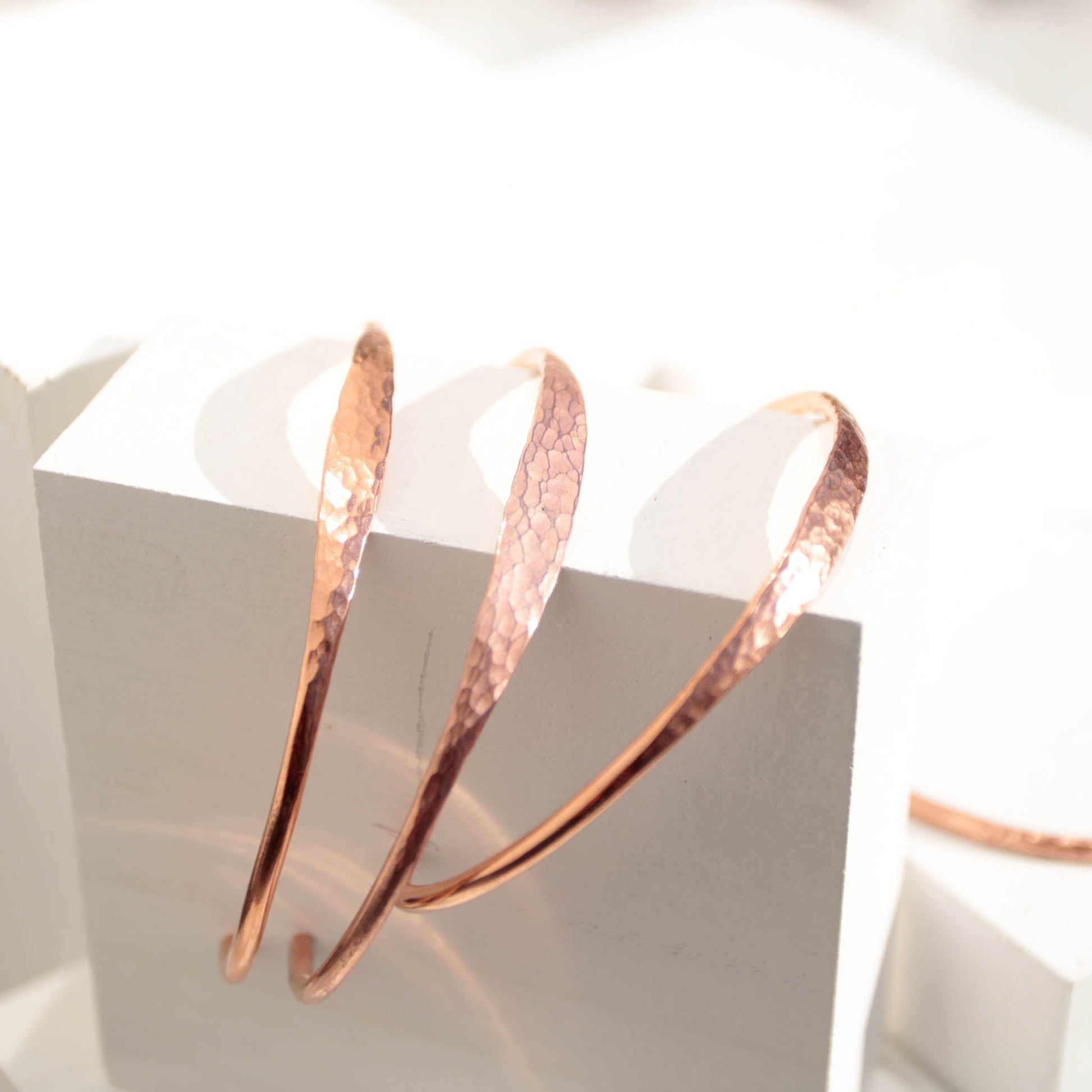 Minimalist hammered copper cuff bracelet with a reflective texture and warm golden glow