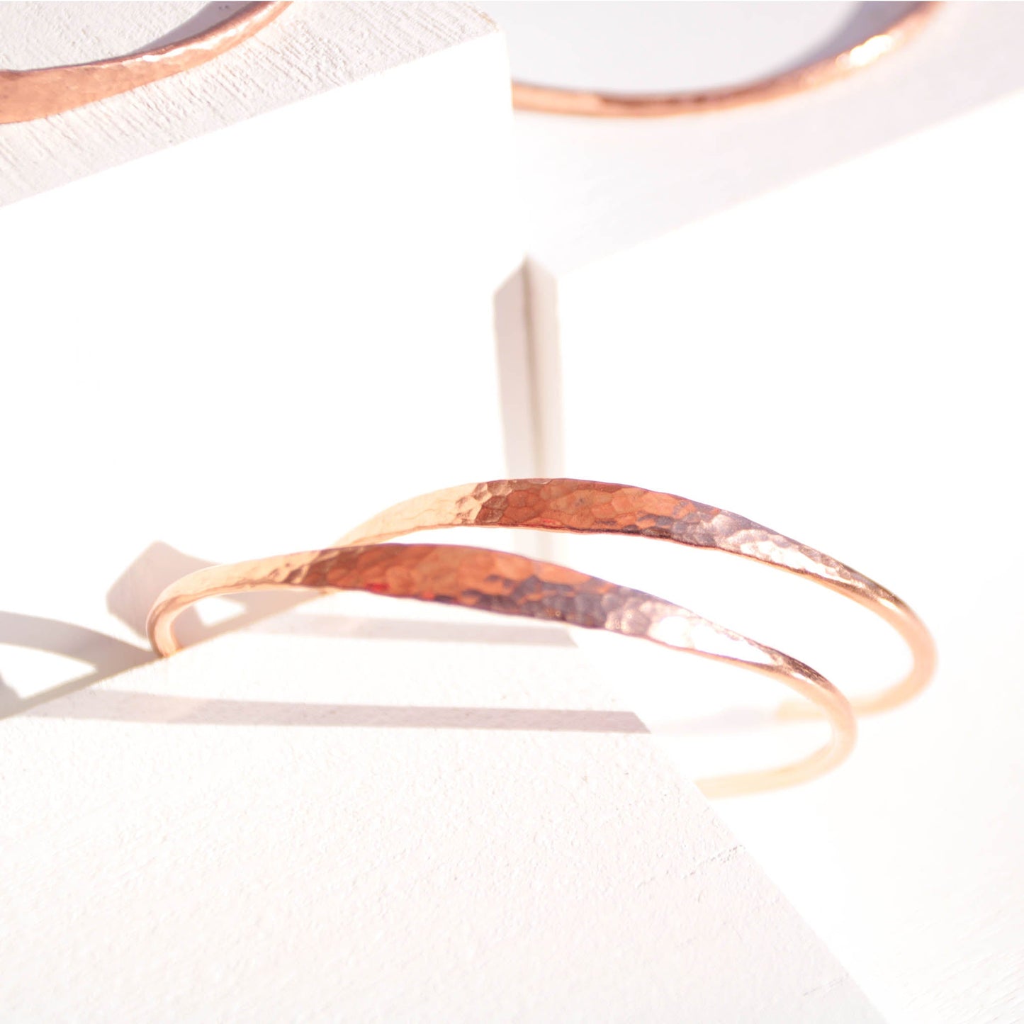 Minimalist hammered copper cuff bracelet with a reflective texture and warm golden glow