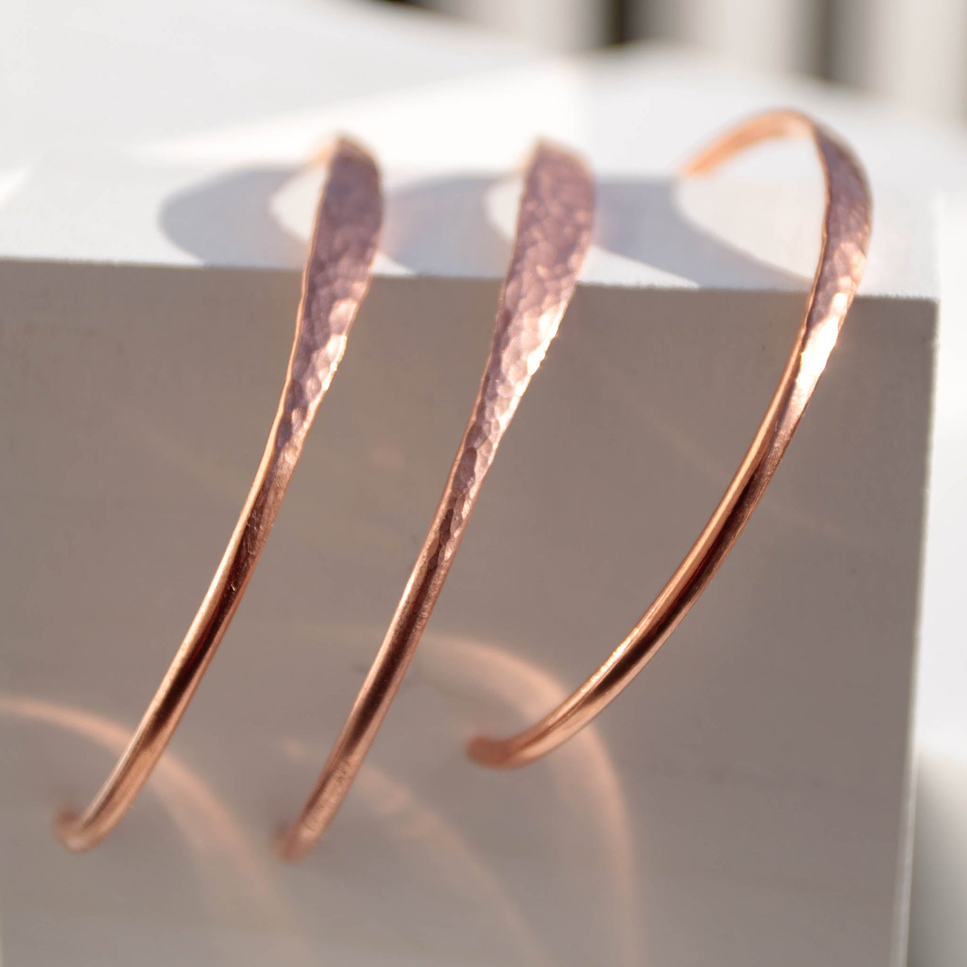 Minimalist hammered copper cuff bracelet with a reflective texture and warm golden glow