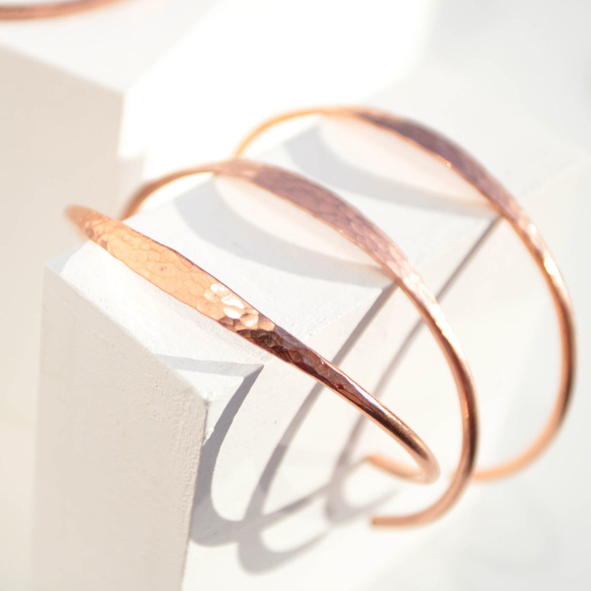 Minimalist hammered copper cuff bracelet with a reflective texture and warm golden glow