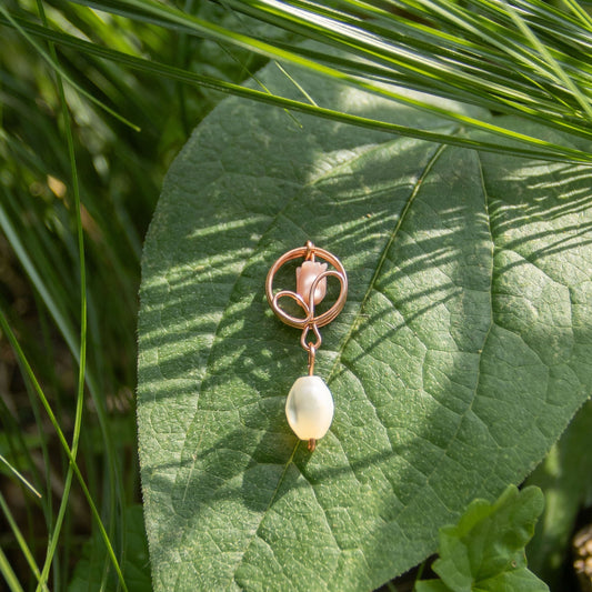 Copper flower bud stud earrings resting on a velvety sage green leaf