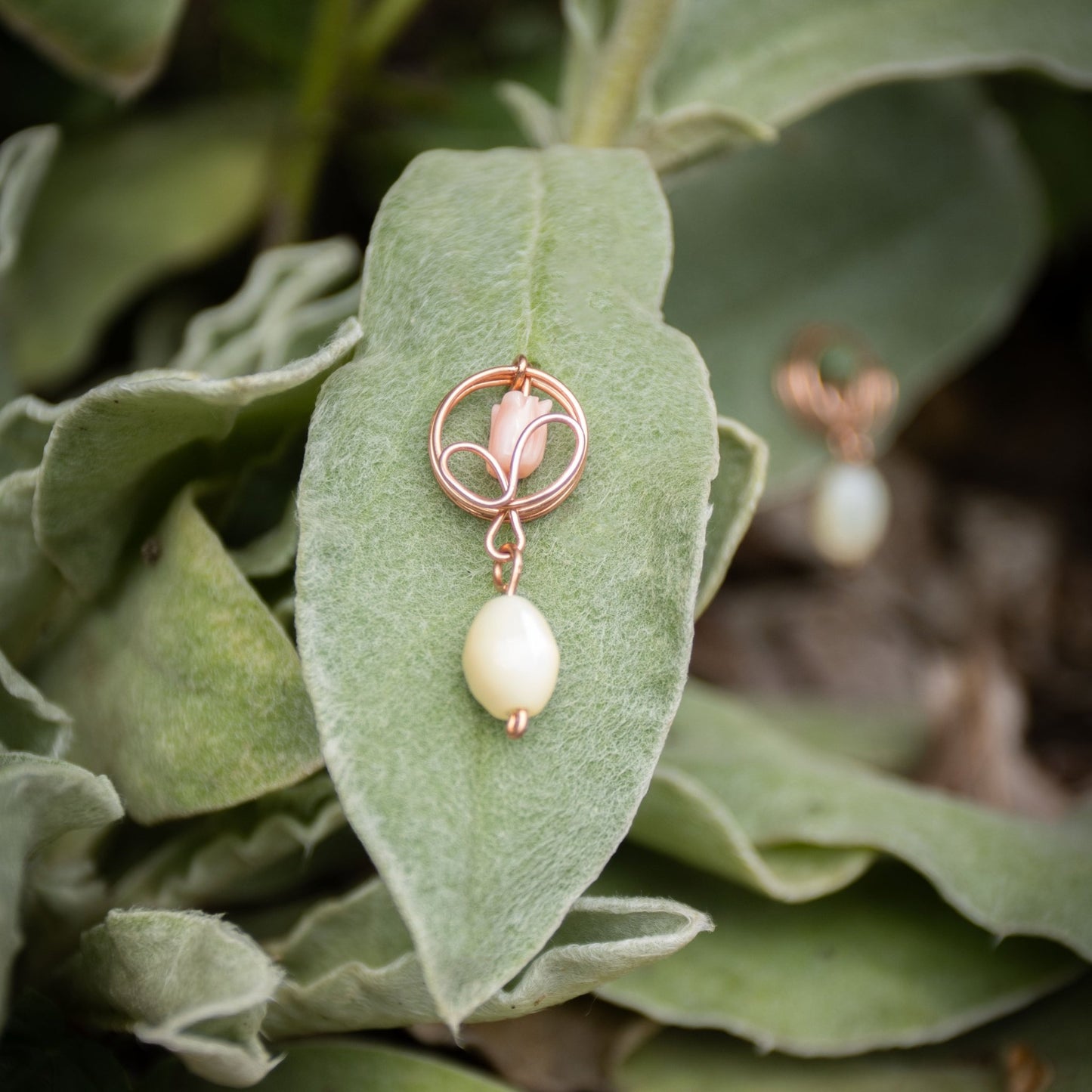 Copper flower bud pendant with freshwater pearl drop on a large green leaf